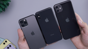 Pictre of three black and gray iphones side by side faced upside down. They are on a light gray table.