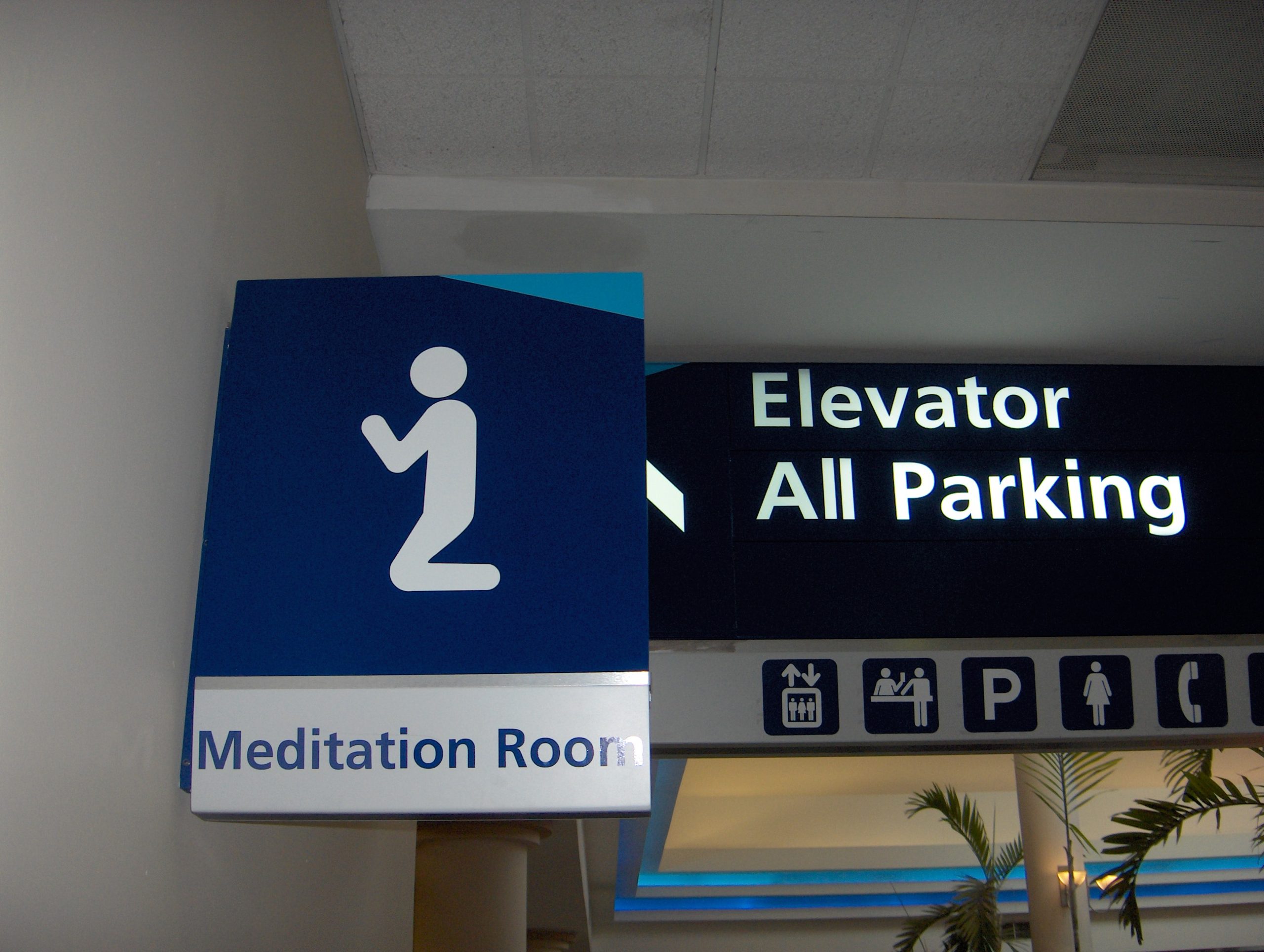 A sign attached to the wall reads," Meditation Room" and uses the generic image of a person kneeling.