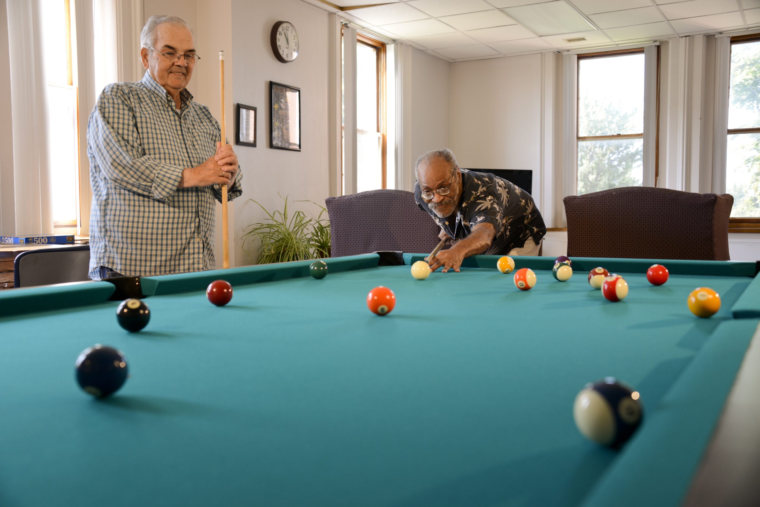 2 older men shooting pool in a community area