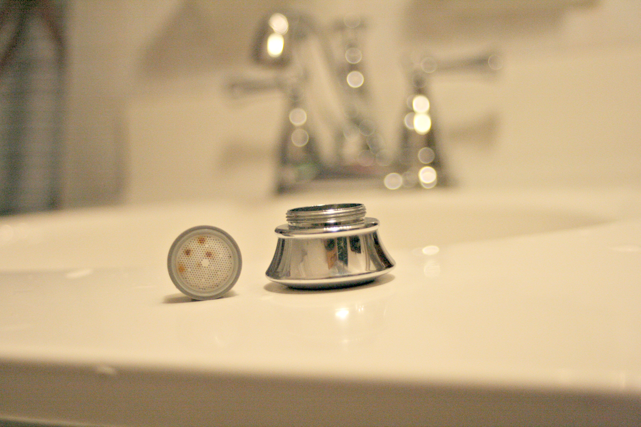 Small stainless steel cylinder. One end screws onto a faucet, the other has 30 tiny holes.