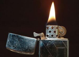 A lit Zippo lighter from 1968 sits in front of a dark background.