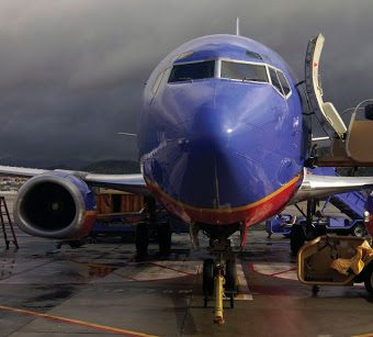 Front-on view of a blue Southwest Airlines plane. Clouds are stormy in the background.