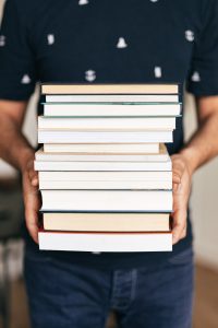 Person holding a stack of textbooks