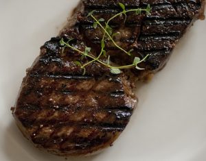 Plated grilled steak garnished with herbs.