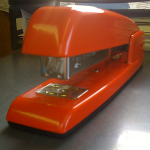 Red Swingline stapler sits on a table.