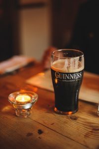 A Guinness Draught beer in a glass next to a candle in an English pub.