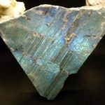 Striations or parallel dark lines on one cleavage surface on plagioclase feldspar that has an iridescent blue-green sheen.