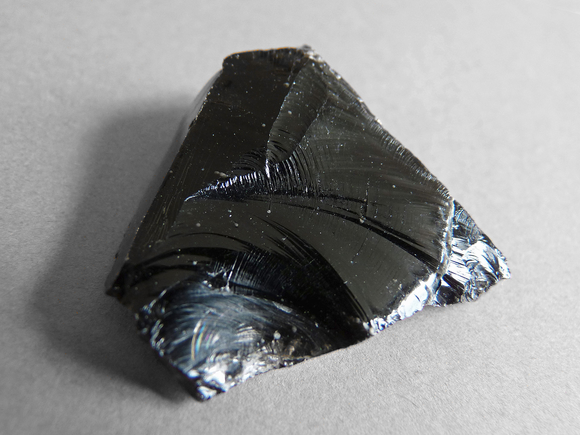 An angular chunk of shiny black volcanic glass that has a conchoidal fracture.