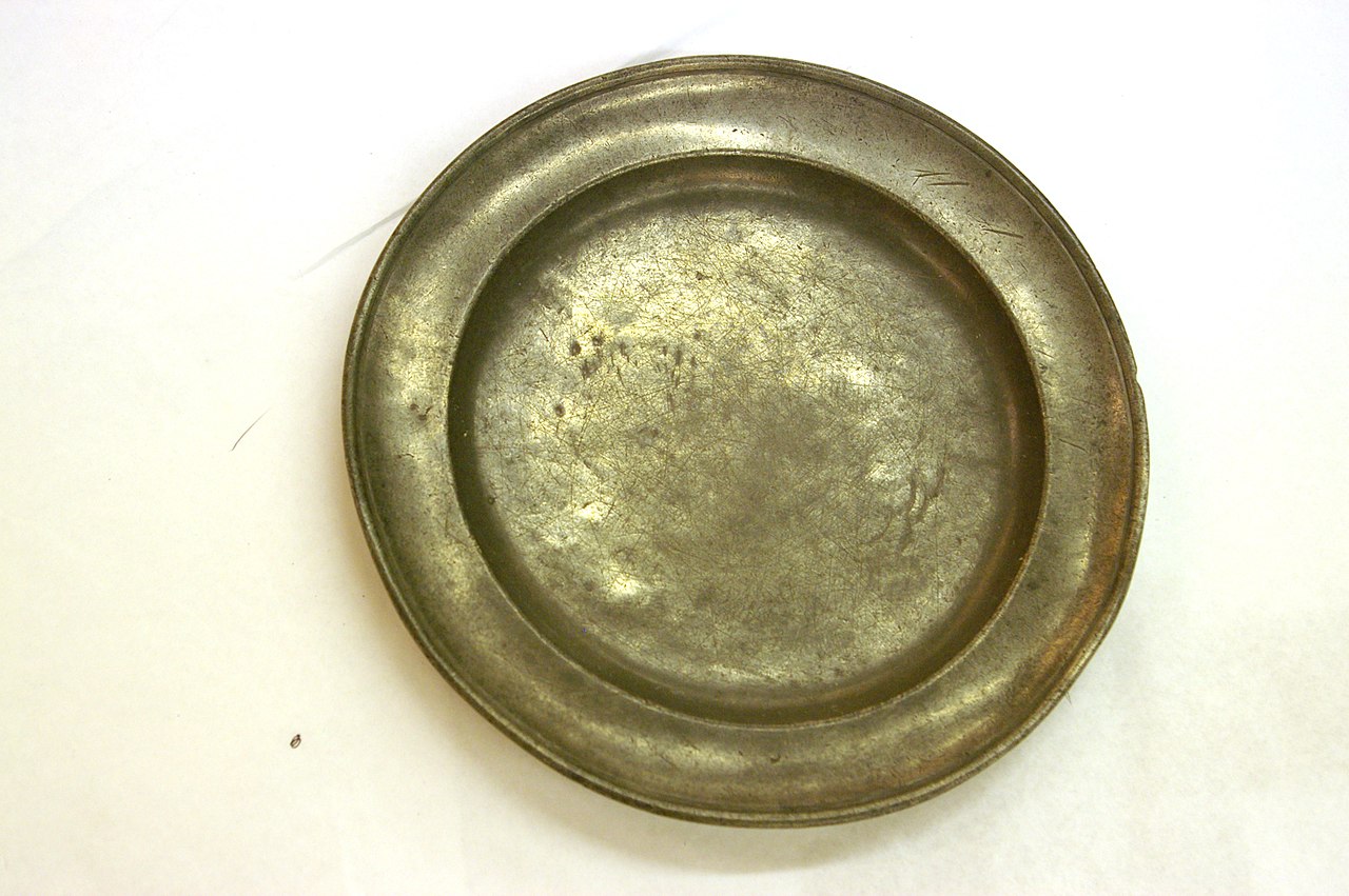 Antique gold-colored pewter plate showing a more dull submetallic luster.