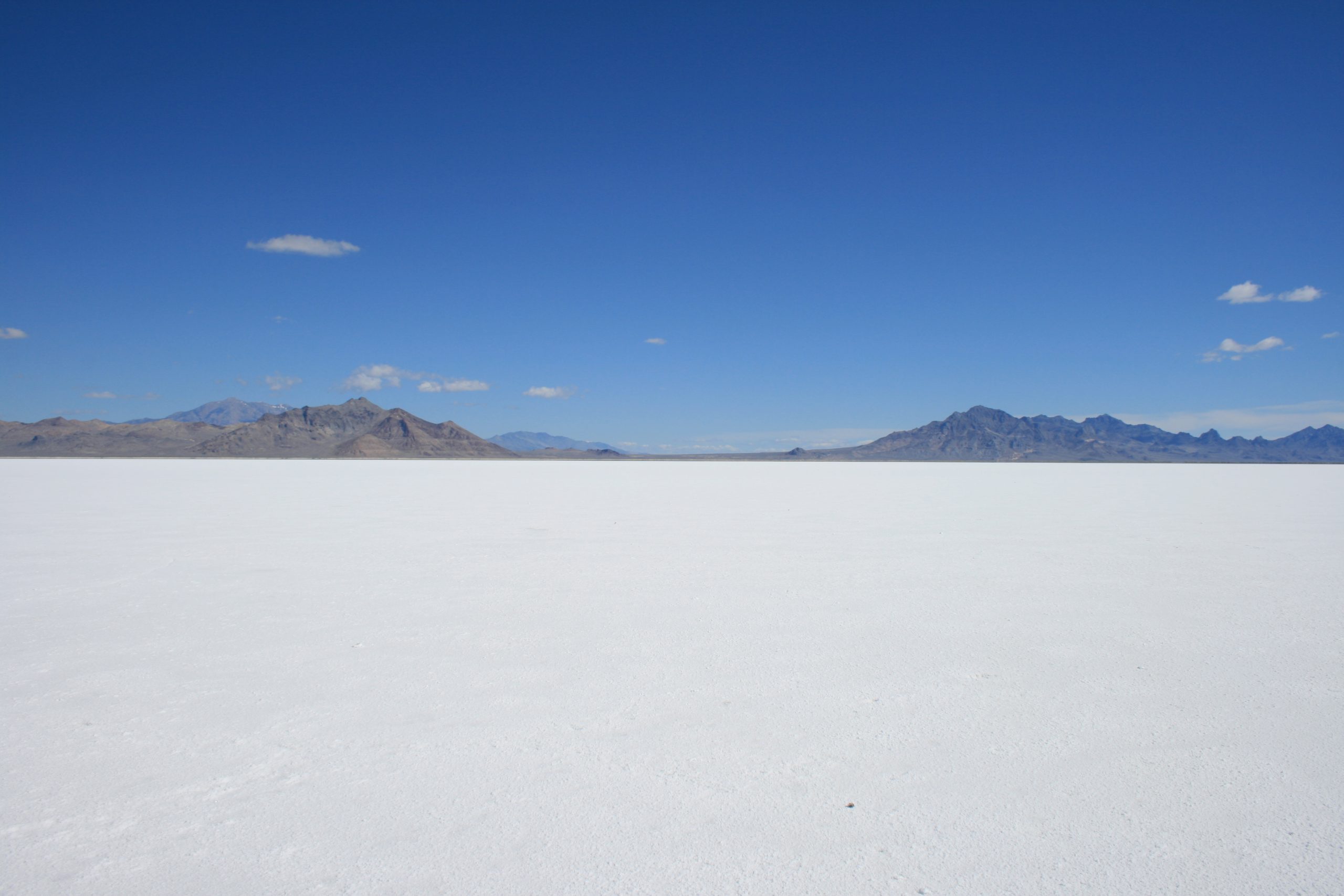 A flat white expanse with a mountain range in the distant background.