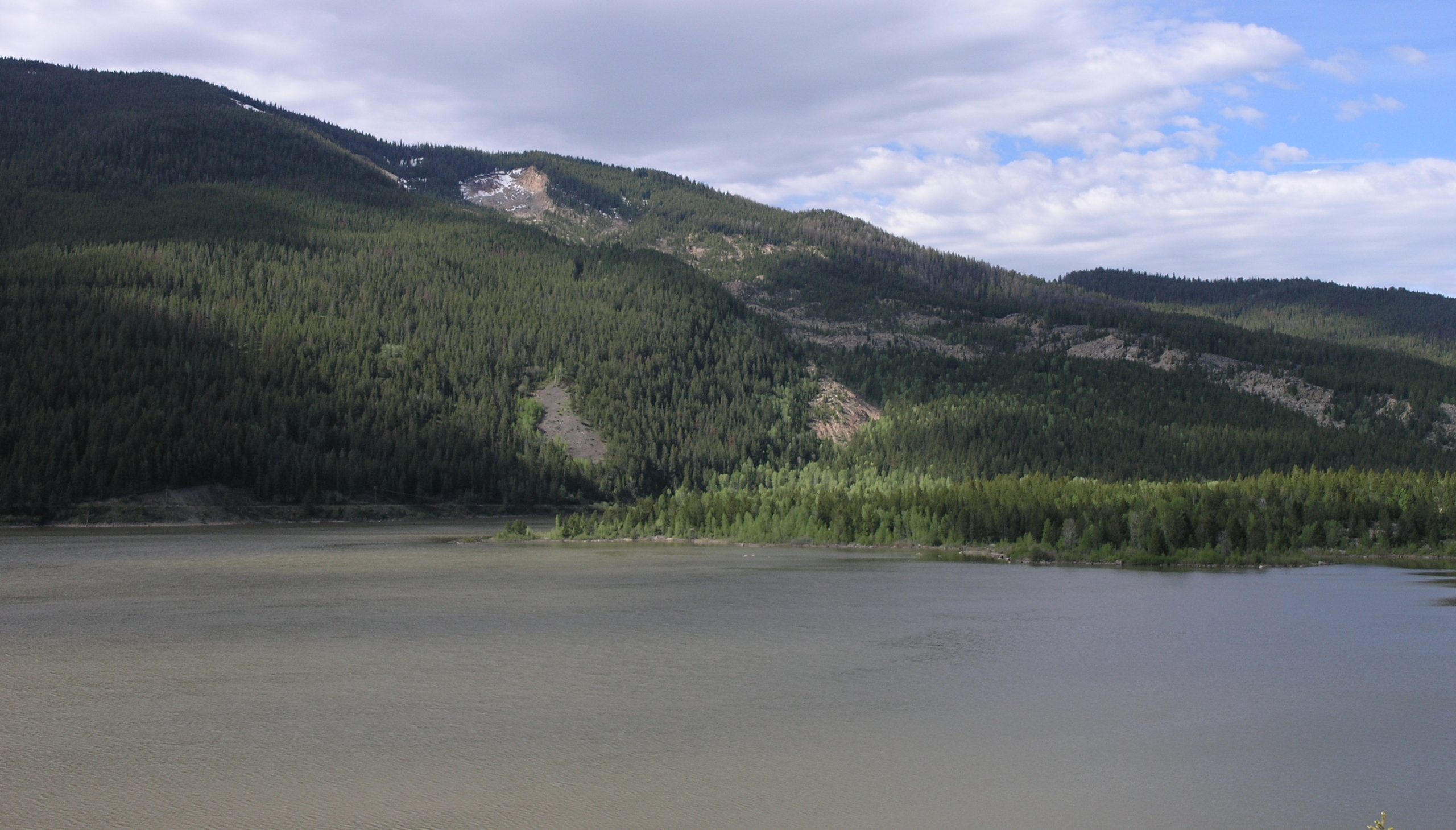 Sloping hillsides covered in vegetation with a lake in the foreground.