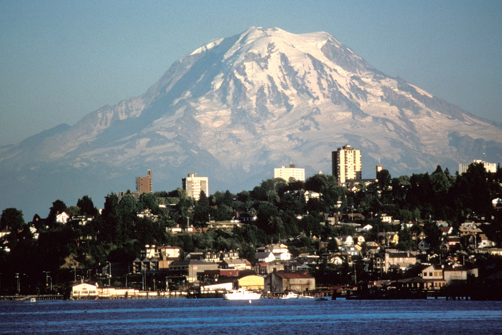 View of city buildings with towering snow-capped mountain in the background.