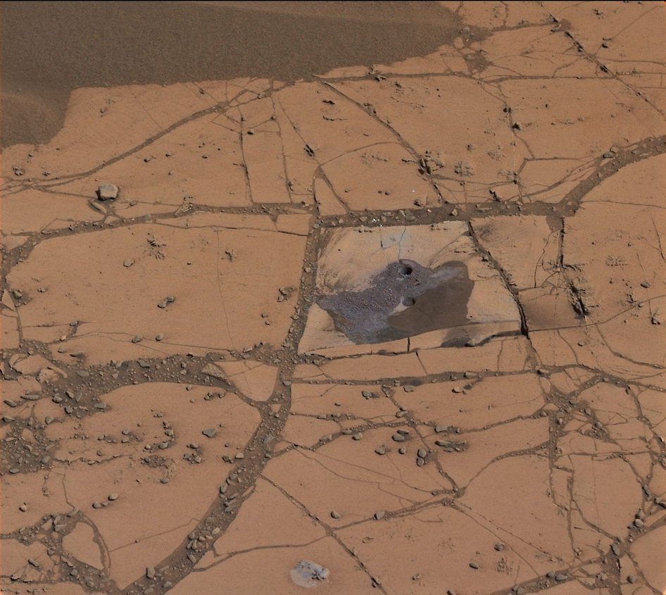 Reddish-brown rock that has a small hole drilled through it.