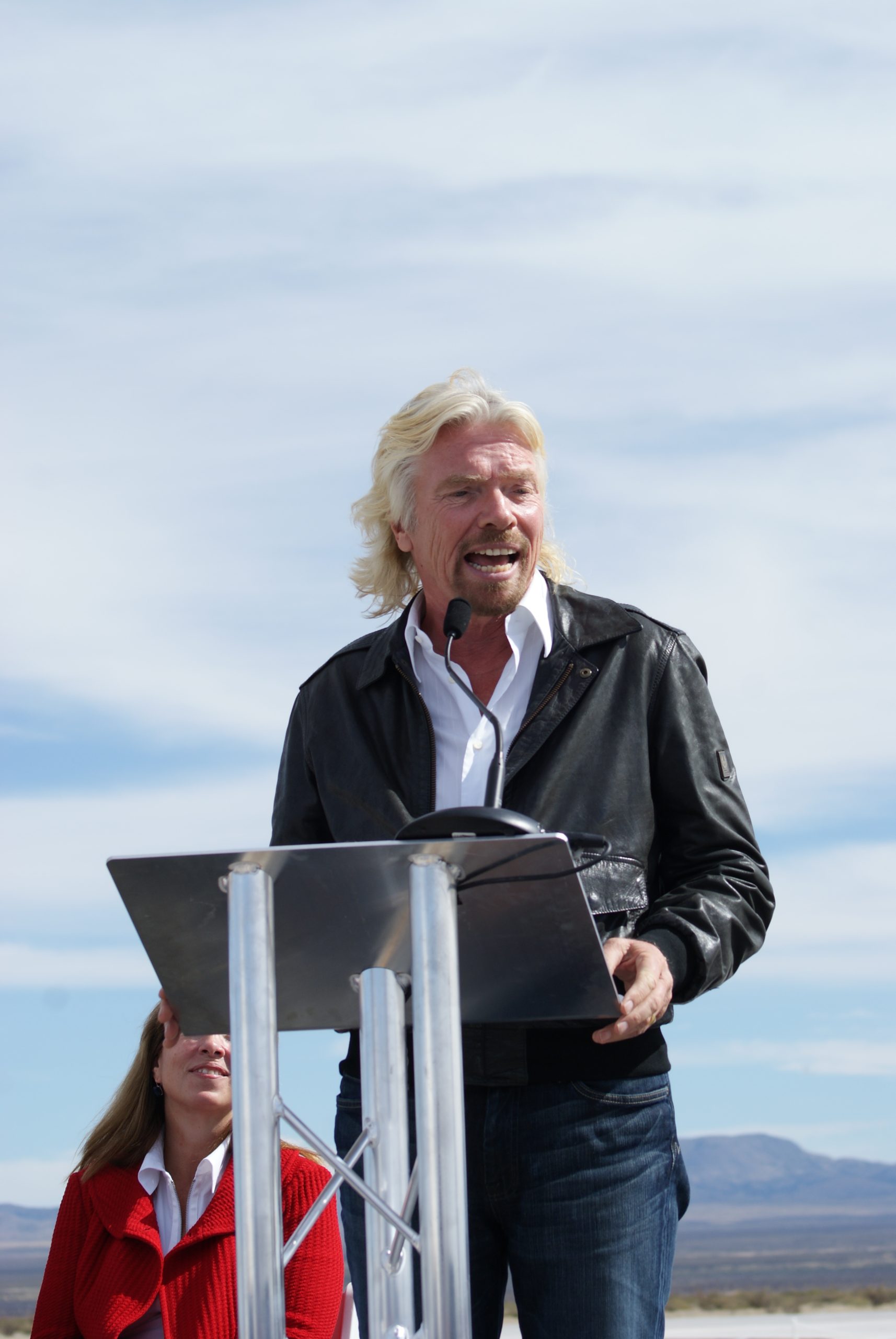 Middle aged white man delivering a speech from behind an outdoor podium