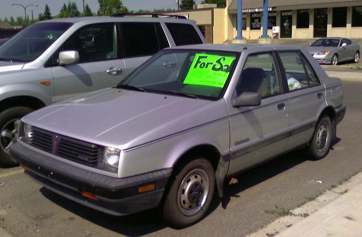 Silver four door sedan with a for sale sign in the window