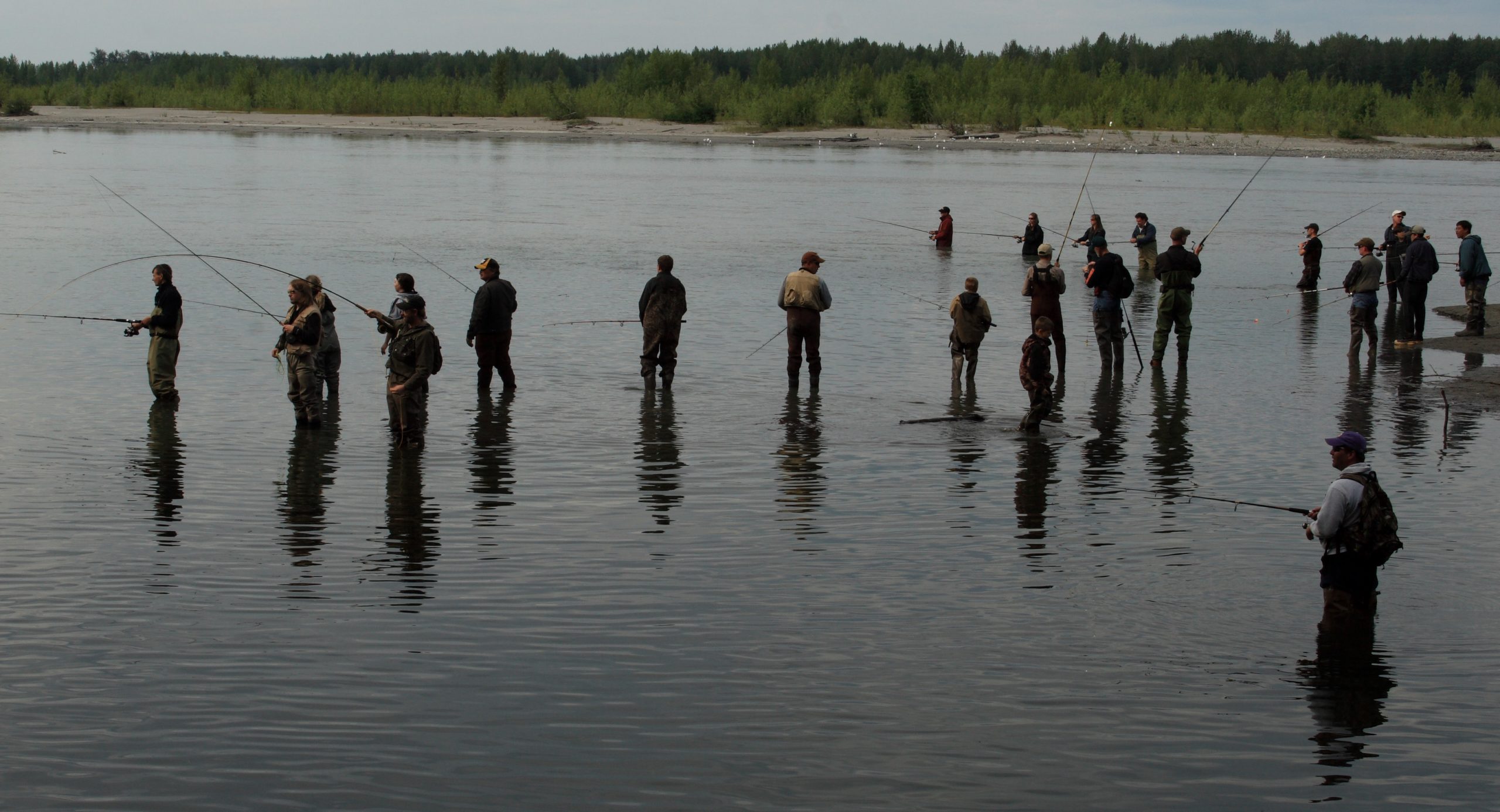 Crowd of people wading in shallow water while recreational fishing