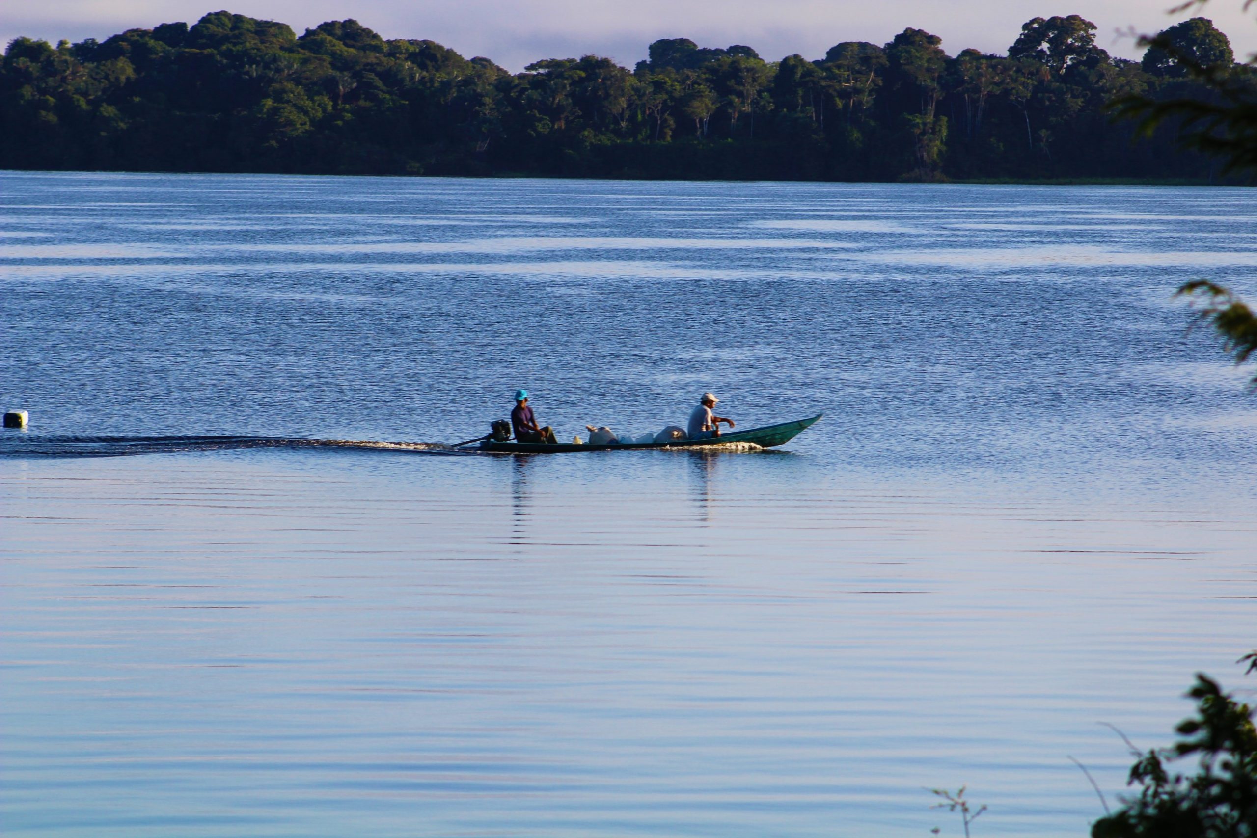Two people traveling on a river in a motorized canoe