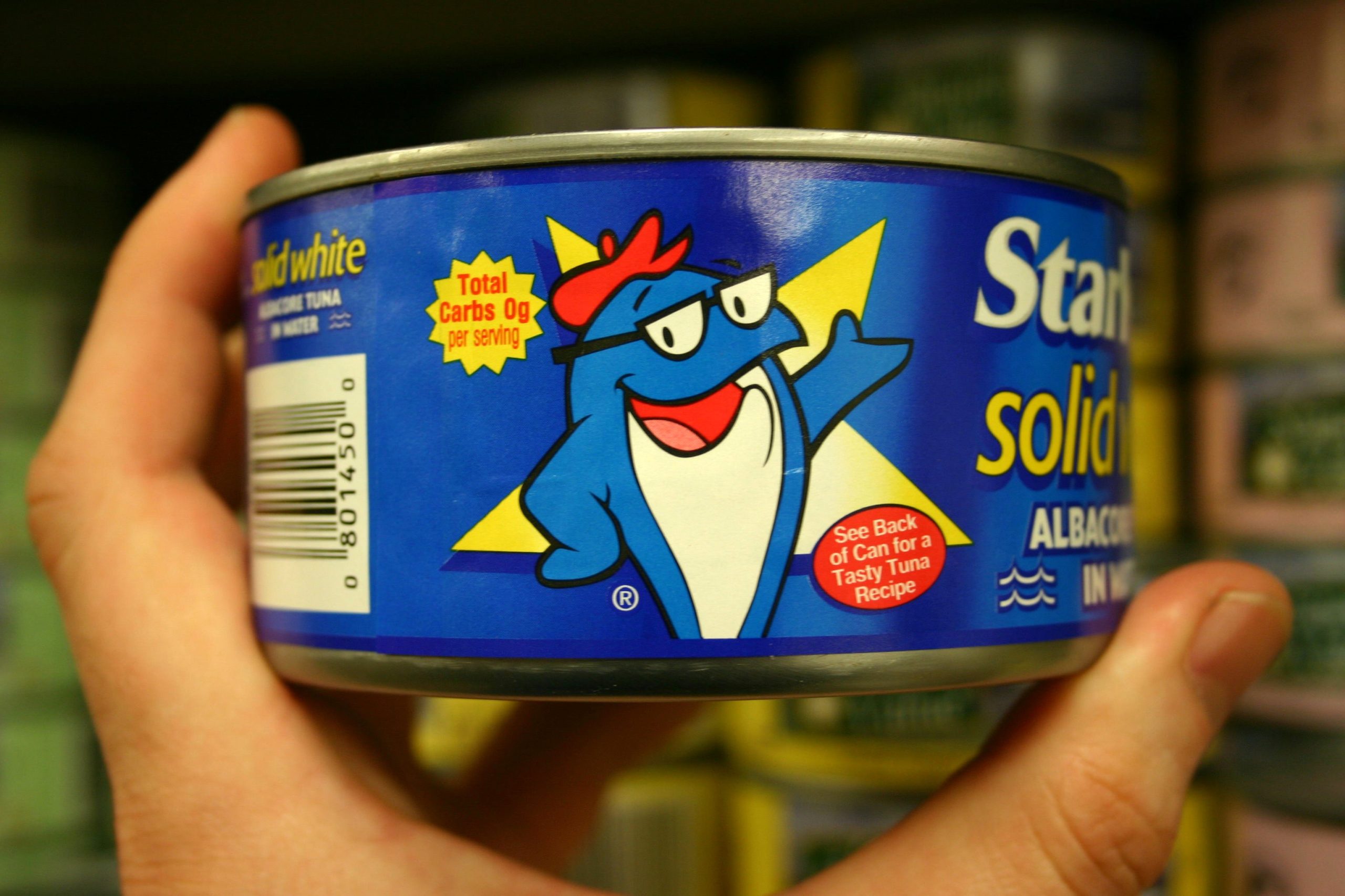 Photograph of someone holding a can of Starkist tuna with image of tuna character displayed