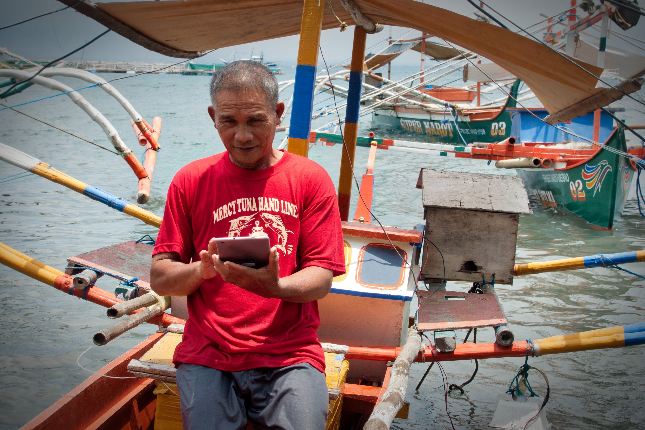 Tuna fisherman enters data on tuna catch with digital device