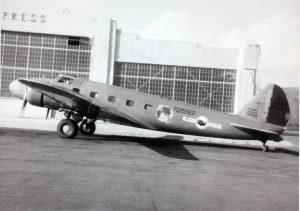 The Boeing 247 is shown taxiing on a runway with its twin propellor engines mounted on the front of the wings near the fuselage. The one shown is a United Air Lines aircraft, with 5 passenger windows shown, each with a rectangular shape, but with rounded corners, rather than sharp corners. Additionally, the wings have a large surface area, along with the rounded vertical tail at the rear of the aircraft.