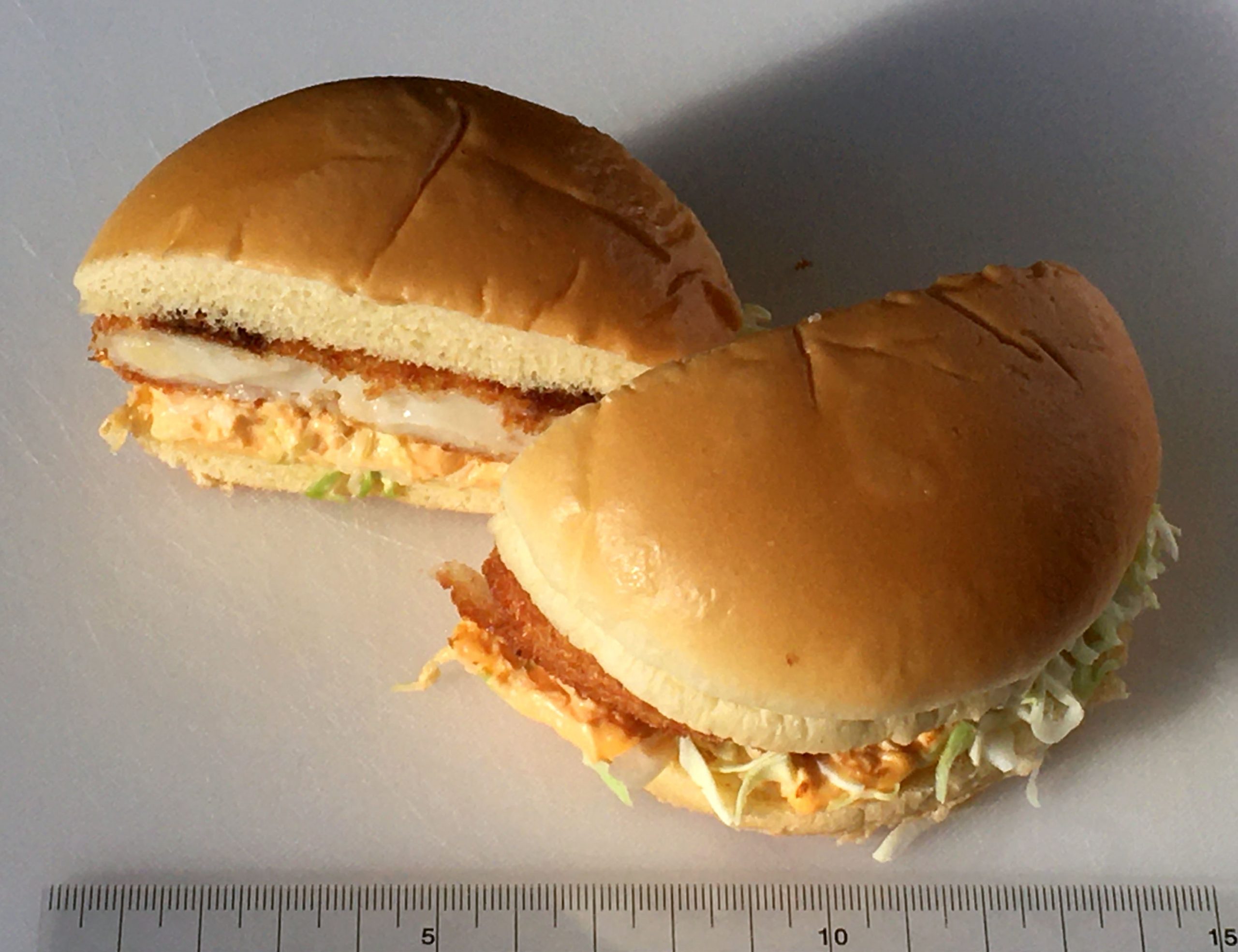 Close up photograph of a Mcdonald's sandwich. The sandwich has lettuce, macaroni, shrimp, and white sauce.