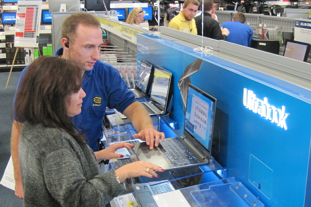 Salesman helps a woman pick out a laptop inside Best Buy.