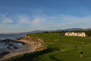 Photo of a golfer on a golf course with mountains, beaches, and a country club in the background.