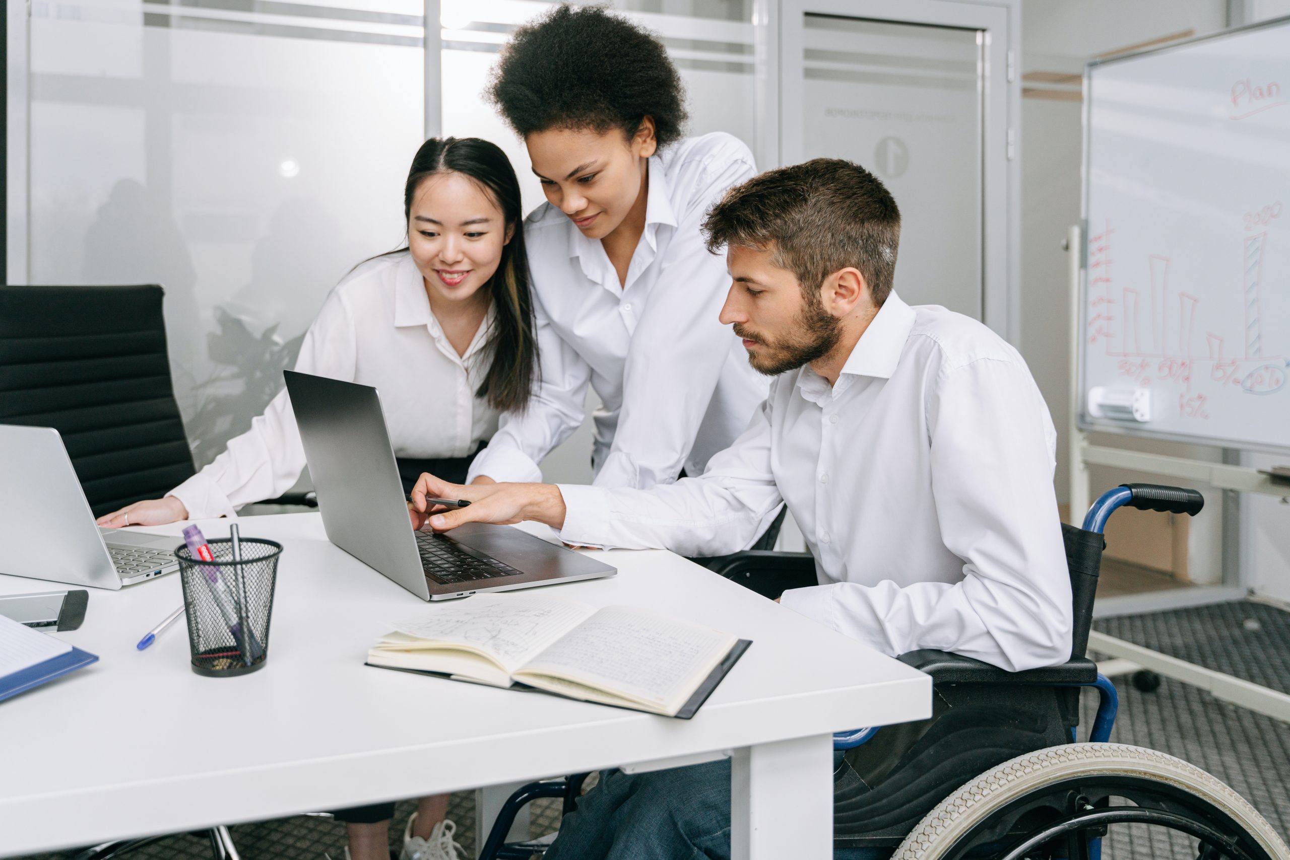 Photo of three people in an office space looking at the same computer screen.