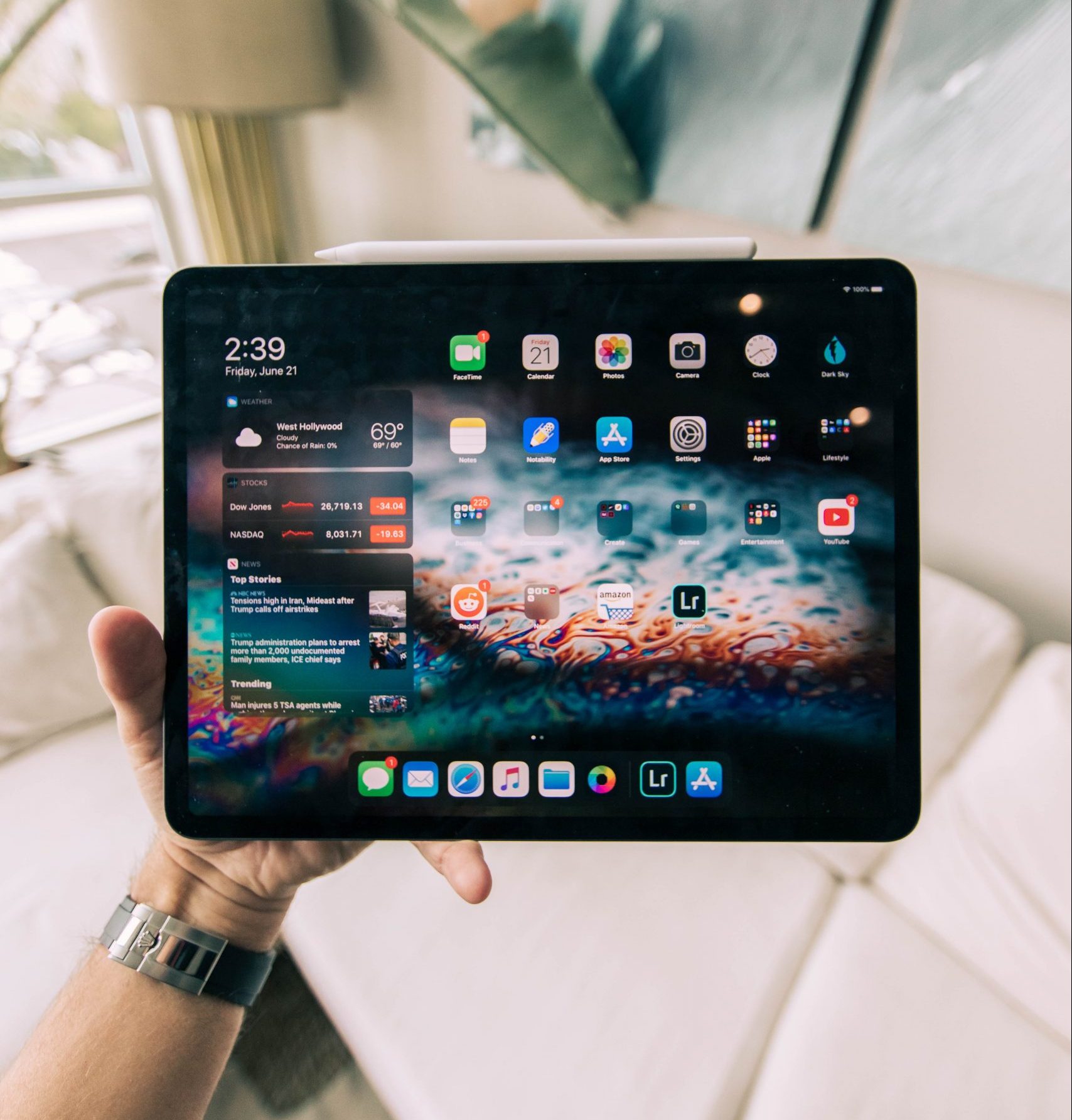 A photograph shows a person holding an iPad pro. There are colorful widgets and apps on the screen.