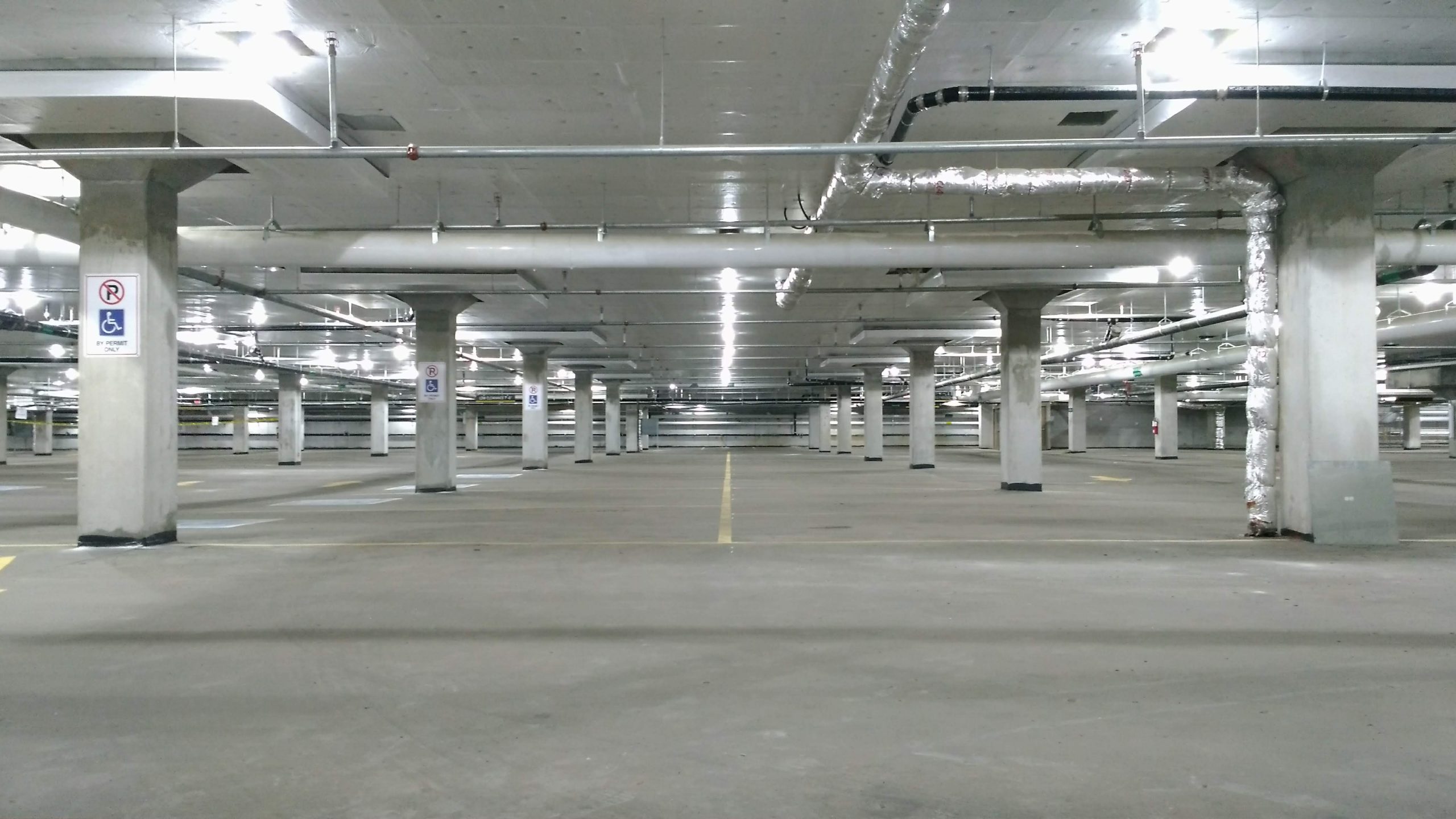 An image of an indoor parking garage with no cars and multiple lines of square columns.