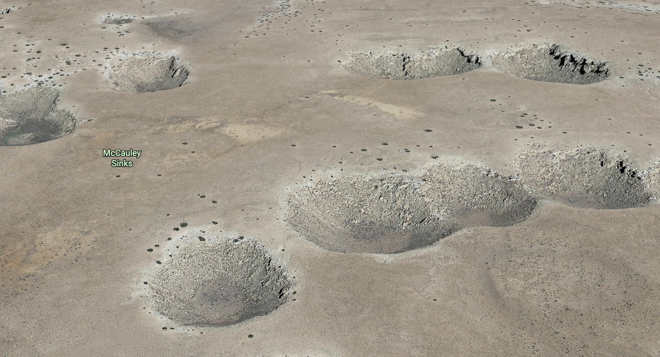 Light tan landscape with numerous bowl-shaped sinkholes.