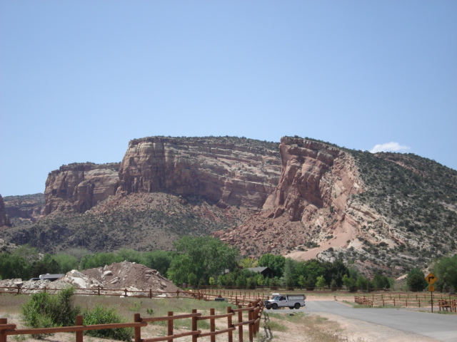 View of a cliffside with a series of tan to red sedimentary layers visible; they are horizontal on the left-hand side and angle downward toward the right.