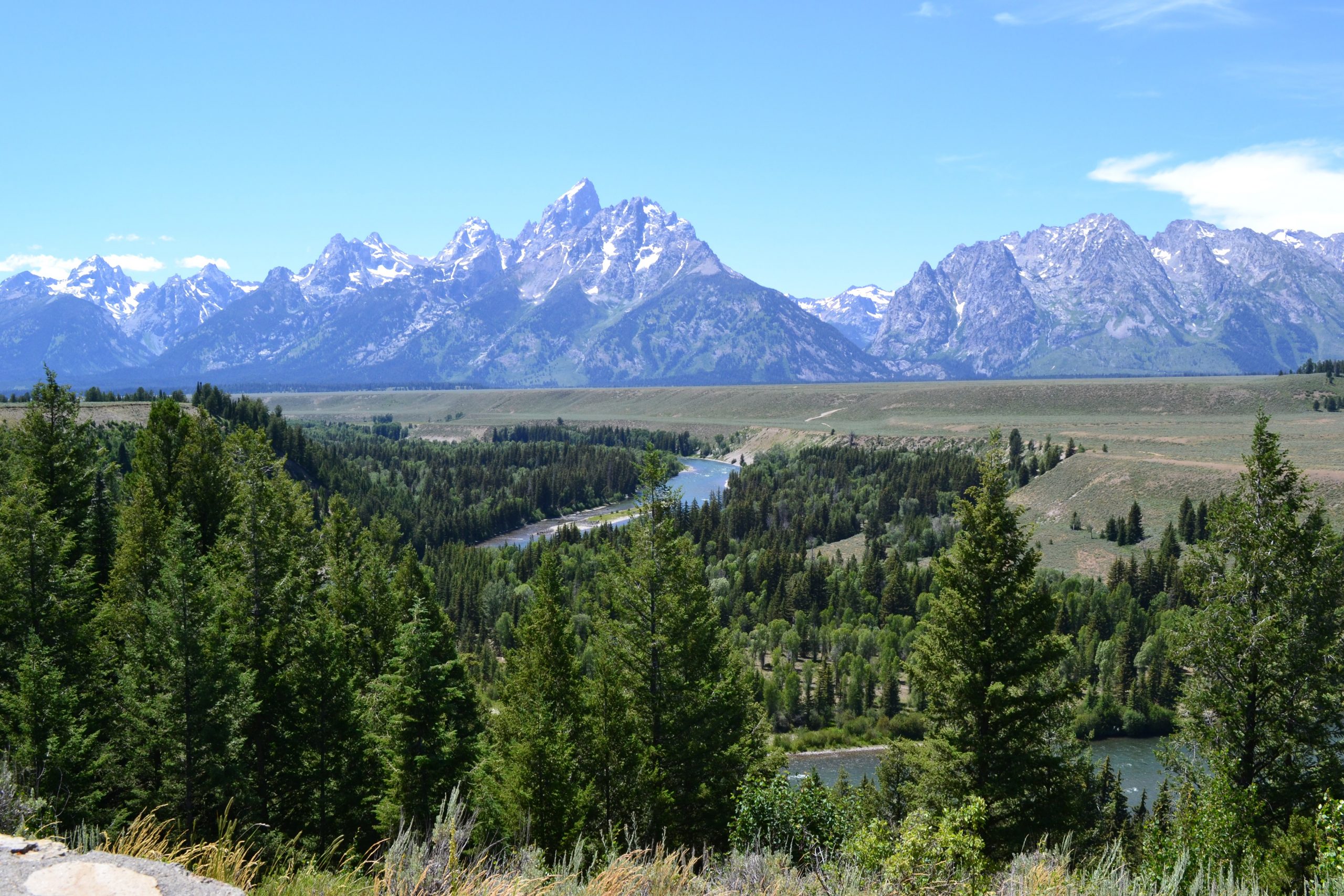 Landscape with a winding river in the foreground and steep rocky mountains in the background. Three different levels of flat surfaces are visible in the foreground.