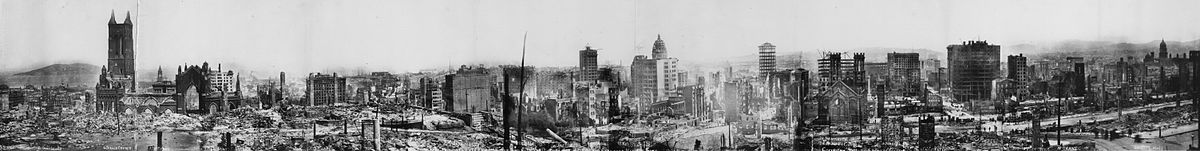 Panoramic black-and-white photo of rubble and the remains of buildings, some still smoking.