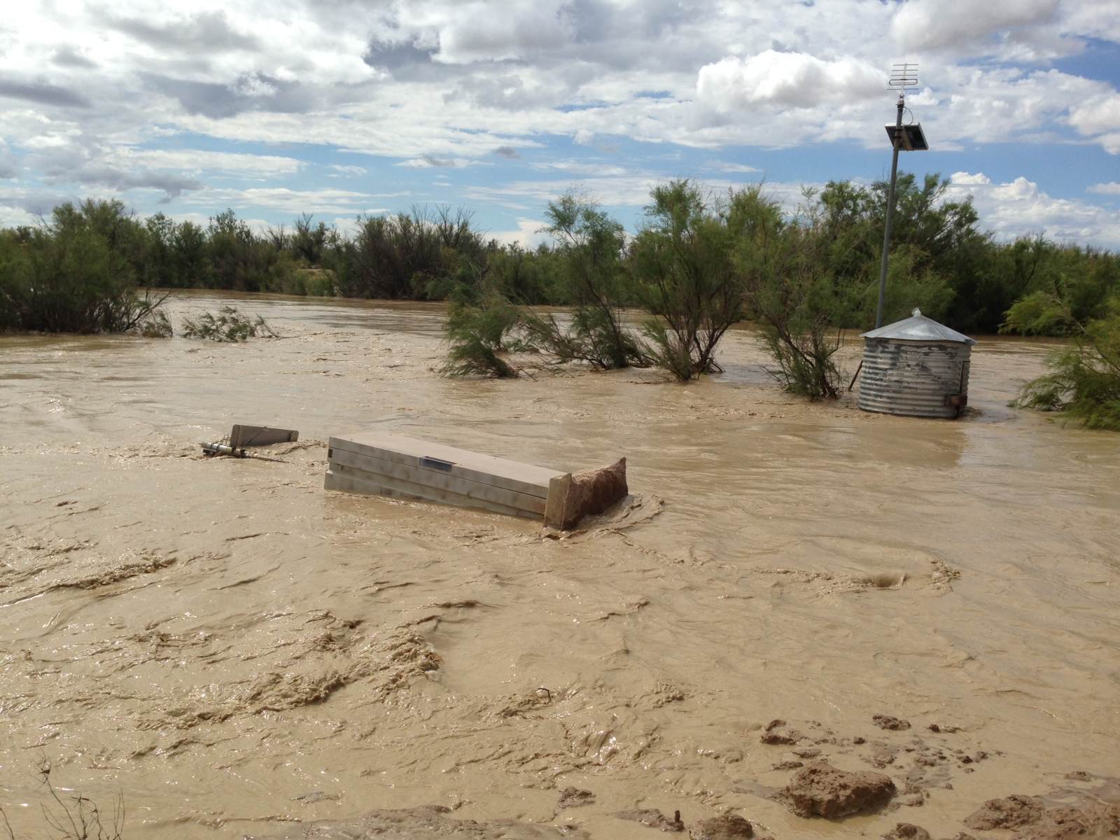 Tan muddy water flooding in the desert.