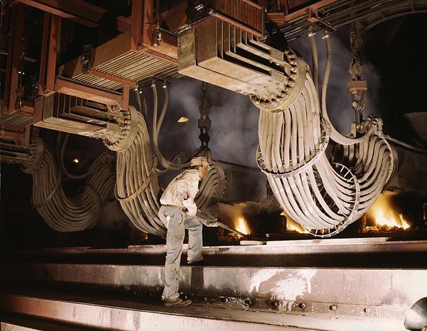 A man is operating a large machine that looks like a blast furnace.