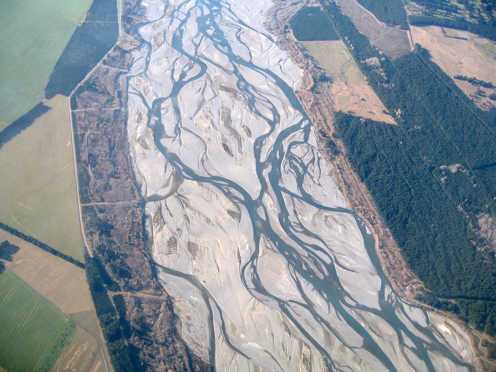 Many channels that braid back and forth among each other; between channels are tan sediment deposits.