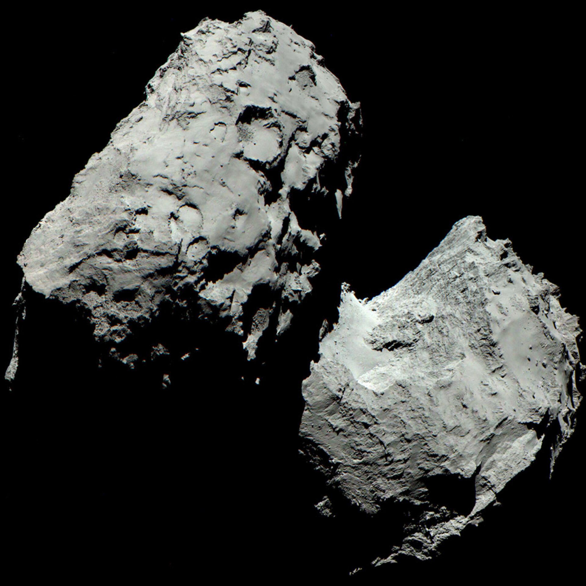 Image of Comet Churyumov-Gerasimenko (67P). Two lobes of this irregularly shaped object are illuminated by sunlight coming from the upper left. Bright streaks of material are seen radiating away from the sunlit surfaces of the comet. These streaks are not seen coming from the shaded portions.