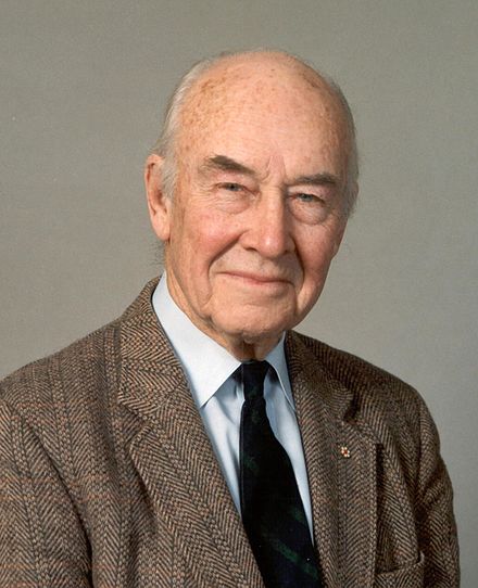 Headshot of an older man wearing a suit and tie.