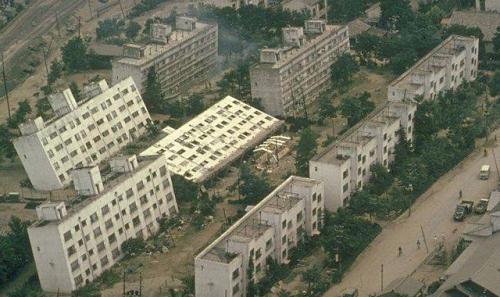 Three rows of rectangular-shaped buildings with the second and third rows of buildings having fallen over.