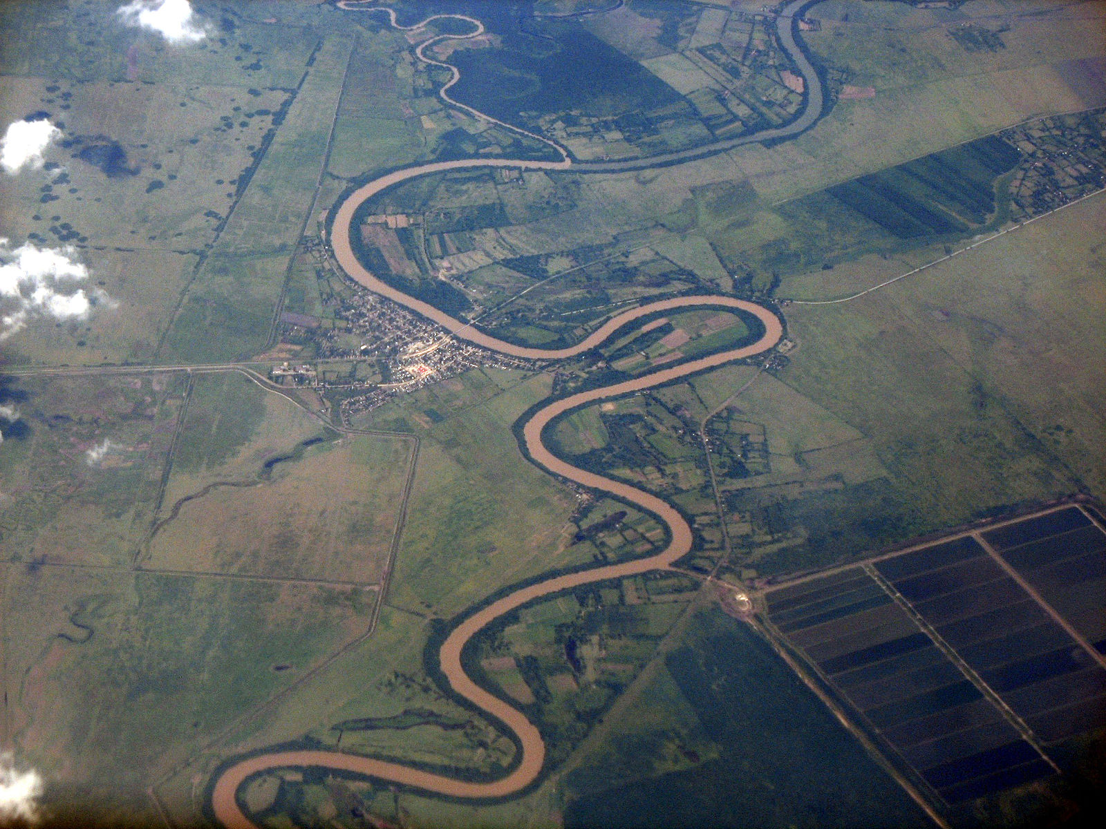 Sinuous tan river running through roughly flat green terrain.