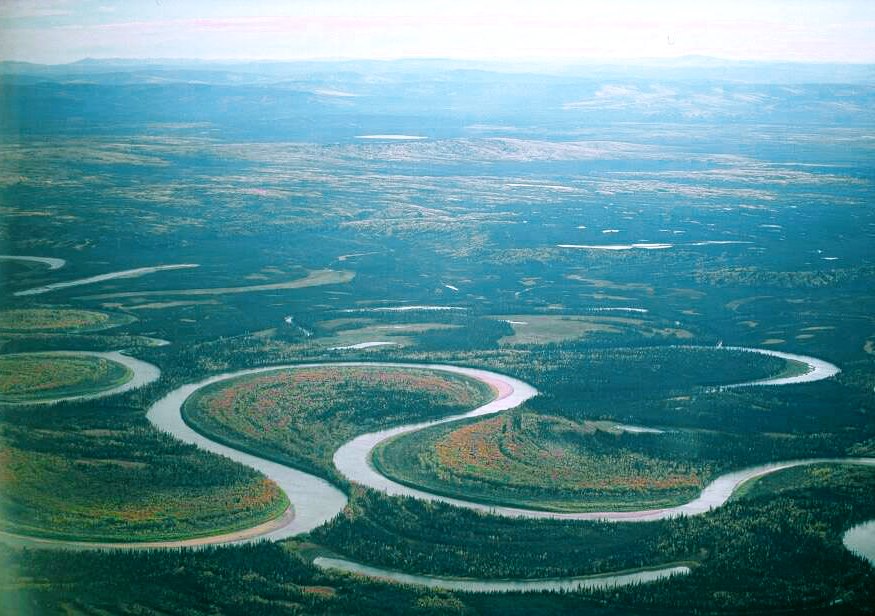 River with extreme S-shaped curves surrounded by flat green landscape; two curves of the river nearly touch each other.