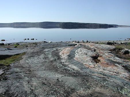 An outcrop of gray and tan rocks on a shoreline.