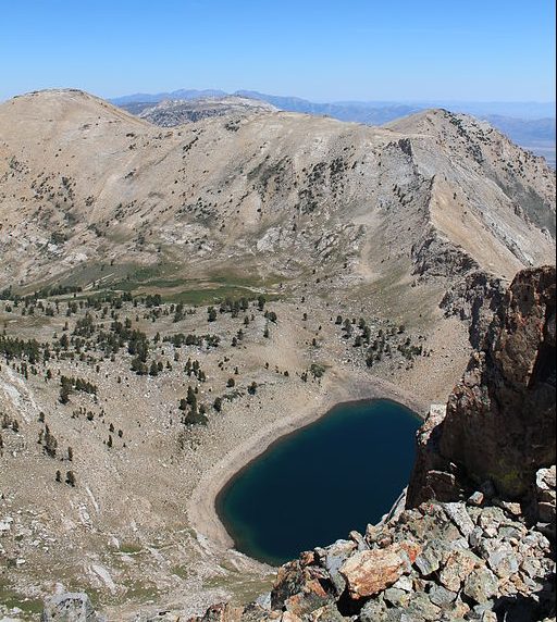 A rocky mountainous area with a circular bowl-shaped valley filled with a lake.