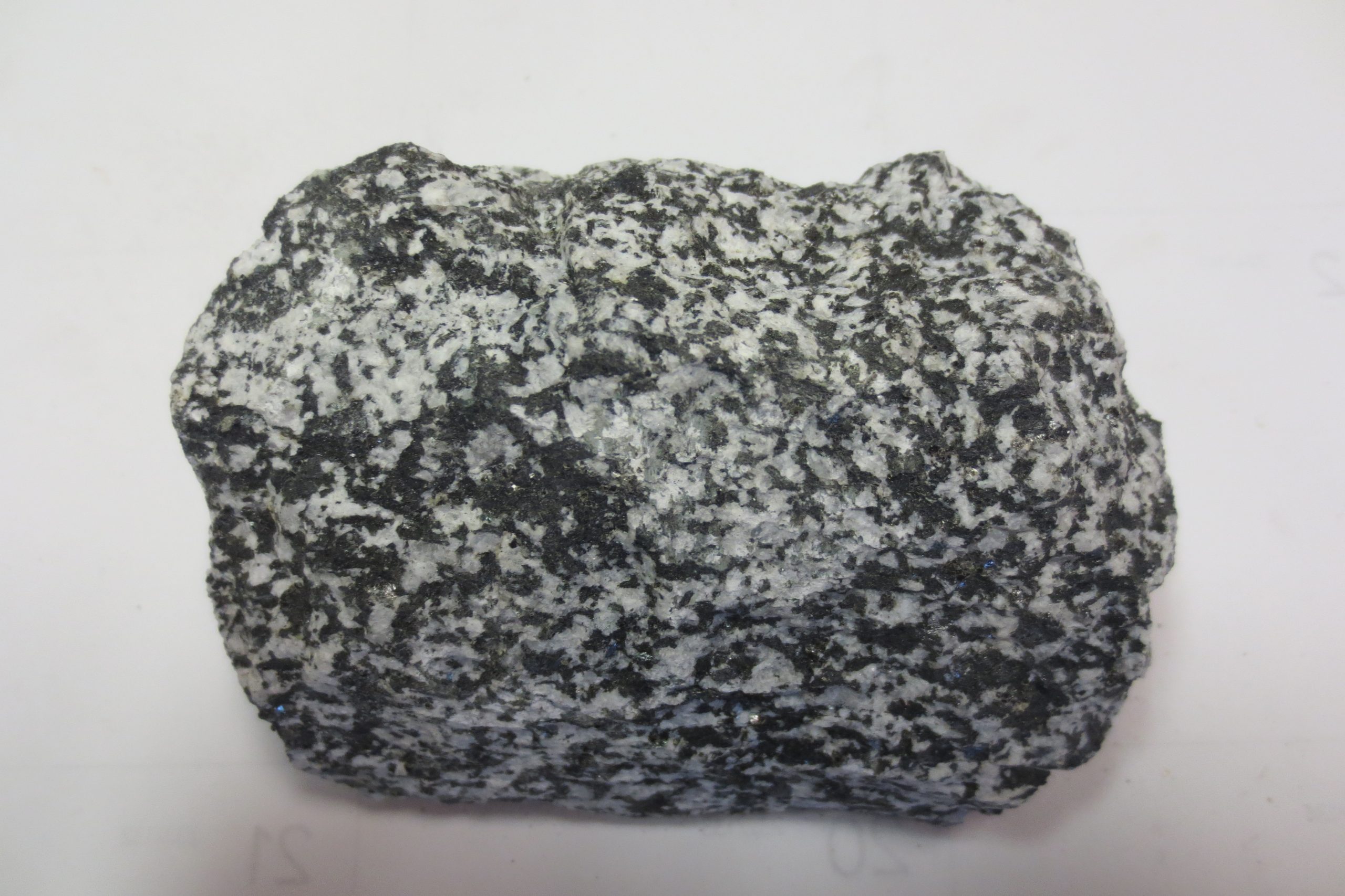 Solid, opaque, roughly rectangular, rough sided rock with specs of black and gray particles