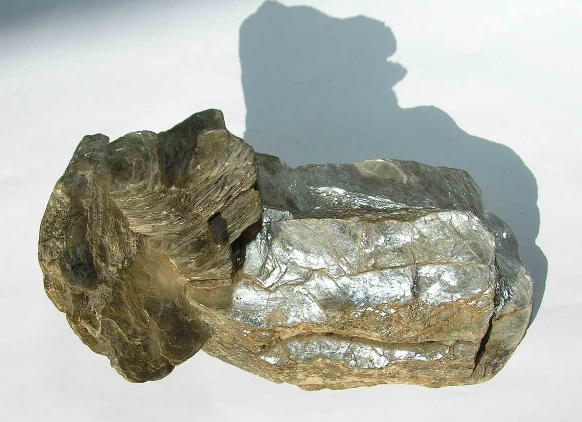 Brown, opaque rock-like mineral with shiny surface that is more cream in color and reflective