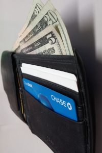 A photograph of an open wallet from the side. Two twenty dollar bills and a five dollar bill stick out of the wallet stacked on top of each other. Two white cards and a Chase card are in the visible.